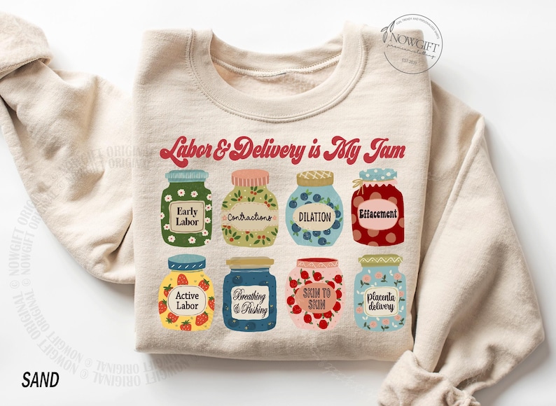 May include: A beige sweatshirt with the text "Labor & Delivery is My Jam" printed in red. The text is surrounded by nine illustrated jars with different stages of labor printed on them.