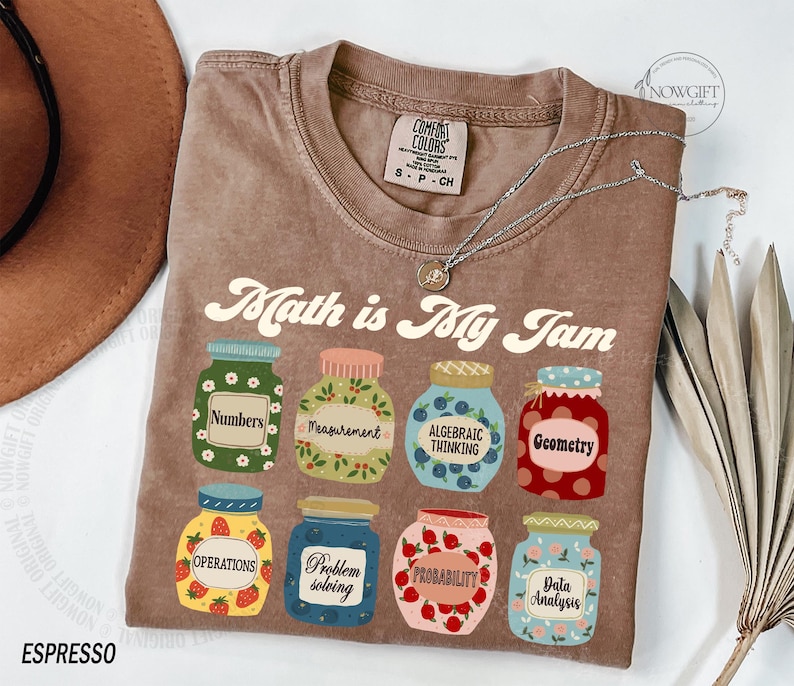 May include: A brown t-shirt with the text "Math is My Jam" printed on it. The text is in a retro font. There are nine jars with different math-related terms printed on them, such as "Numbers", "Measurement", "Algebraic Thinking", "Geometry", "Operations", "Problem Solving", "Probability", and "Data Analysis".
