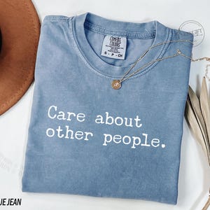 Puede incluir: Una camiseta azul jean con el texto "Care about other people." impreso en blanco.