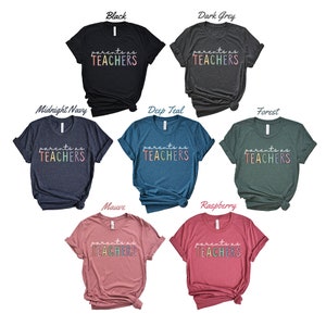 Puede incluir: Un conjunto de diez camisetas de varios colores con el texto "parents as teachers" en un degradado arco&iacute;ris. Las camisetas se muestran sobre un fondo blanco.
