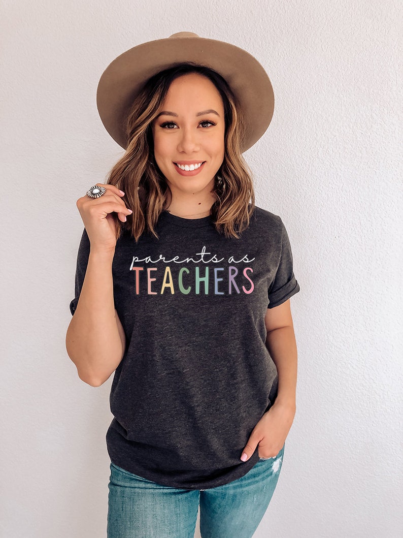Puede incluir: Una camiseta gris oscuro con el texto "parents as TEACHERS" en colores arco&iacute;ris.