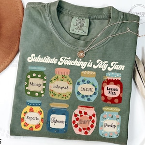May include: A green t-shirt with the text "Substitute Teaching is My Jam" printed on it. The text is in a retro font. There are eight jars with different words on them, including "Manage", "Interpret", "Execute", "Lesson Plan", "Reports", "Supervise", "Adapt", and "Develop".