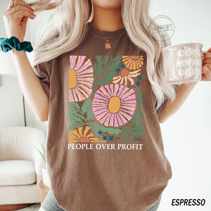 May include: A brown t-shirt with a graphic of colorful flowers and the text "People Over Profit".