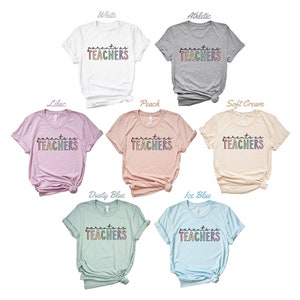 Puede incluir: Un conjunto de diez camisetas de diferentes colores, cada una con el texto "parents as TEACHERS" en letras arco&iacute;ris.