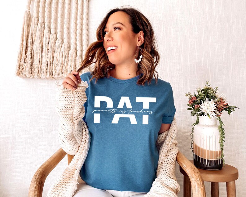 May include: A blue t-shirt with the text "PAT" in white letters. The text "parents as teachers" is written in smaller white letters below the "PAT".