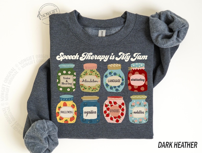 May include: Dark heather grey sweatshirt with the text "Speech Therapy is My Jam" in white. The design features nine colorful jars with speech therapy related words like "voice & hearing", "articulation", "language", "stuttering", "swallowing", "cognition", "social", and "modalities".