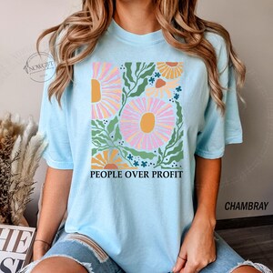 May include: A light blue t-shirt with a floral design and the text "People Over Profit".