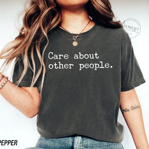 Puede incluir: Una camiseta gris oscura con el texto "Care about other people." impreso en blanco.