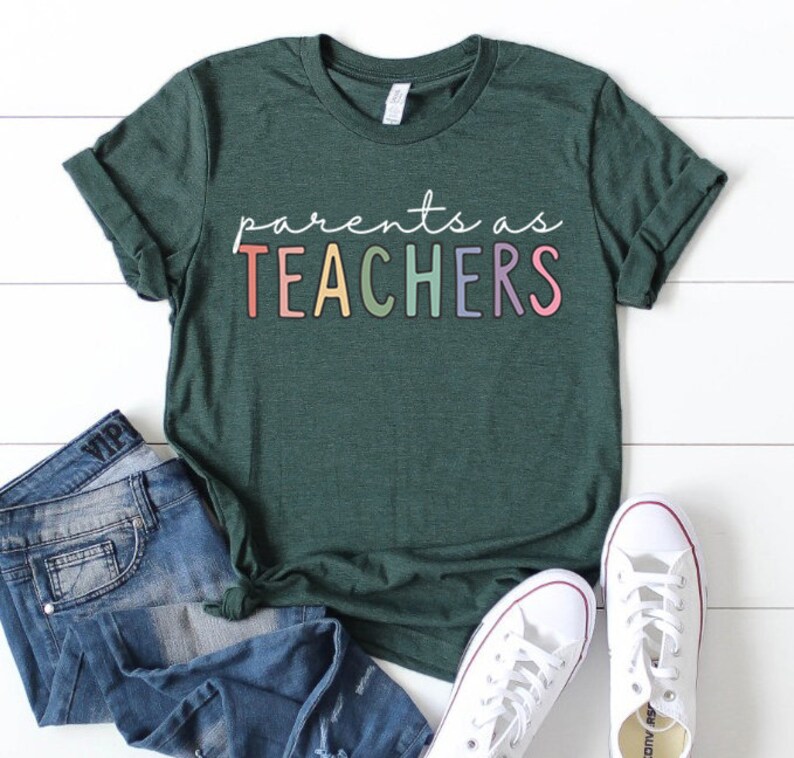 Puede incluir: Una camiseta verde oscuro con el texto "parents as TEACHERS" en colores arco&iacute;ris.