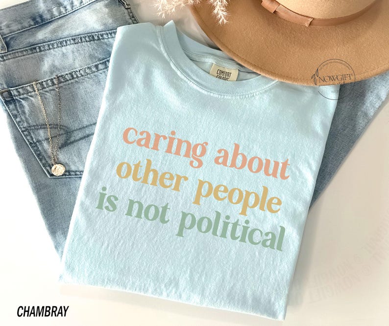 May include: A light blue t-shirt with the text "caring about other people is not political" printed in a rainbow color scheme.