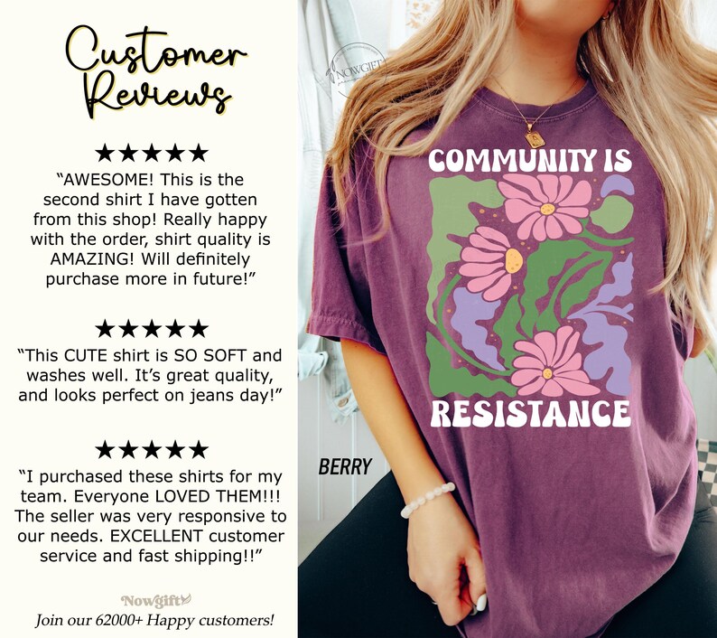 May include: Purple t-shirt with a graphic design of pink flowers and green leaves. The text "COMMUNITY IS RESISTANCE" is printed in white on the shirt.