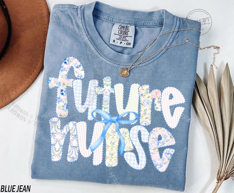 May include: A blue jean Comfort Colors t-shirt with the words "Future Nurse" in white, floral, and gingham patches. A light blue bow is centered below the word "future". A gold necklace with a pendant is draped across the shirt.