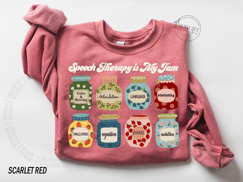 May include: A pink sweatshirt with the text "Speech Therapy is My Jam" in a retro font. The text is surrounded by illustrations of jars of jam, each representing a different aspect of speech therapy, such as voice and hearing, articulation, language, stuttering, swallowing, cognition, social, and modalities.