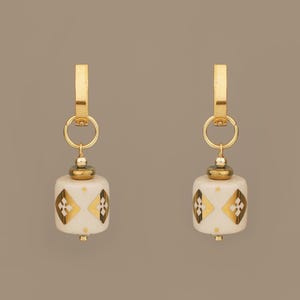 Pendientes colgantes de cerámica hechos a mano con detalles dorados, joyería folclórica en beige y dorado.