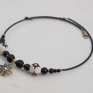 May include: A black choker necklace with black and white beads and a gold star pendant.