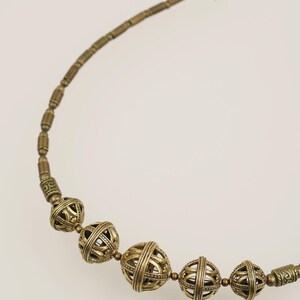 May include: A vintage-style necklace featuring a series of ornate, openwork metal beads in a warm, antique gold color. The necklace has a delicate chain and clasp, with the focal point being the spherical, cage-like beads.