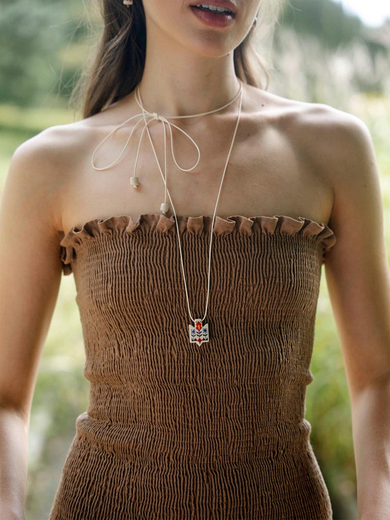 Handmade ceramic wrap necklace featuring a hand-painted Ukrainian Trident pendant with traditional folk flower design in red, blue, green and yellow.