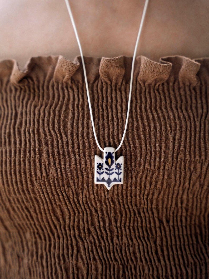 Handmade ceramic wrap necklace featuring a hand-painted Ukrainian Trident pendant with traditional folk flower design in navy color.