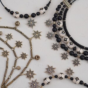 May include: A set of three necklaces featuring black and white beads with star-shaped charms. The necklaces are made of different materials, including metal, wood, and plastic.