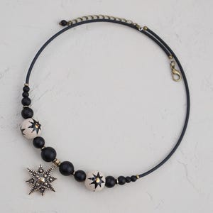 May include: A black choker necklace with white and black star-shaped beads and a large silver star pendant.