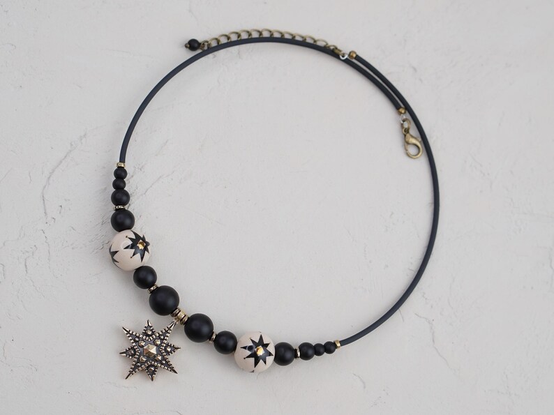 May include: A black choker necklace with white and black star-shaped beads and a large silver star pendant.
