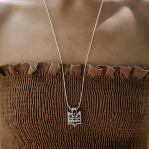 Handmade ceramic wrap necklace featuring a hand-painted Ukrainian Trident pendant with traditional folk flower design in navy.