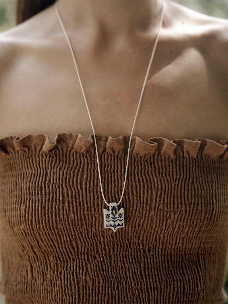 Handmade ceramic wrap necklace featuring a hand-painted Ukrainian Trident pendant with traditional folk flower design in navy.