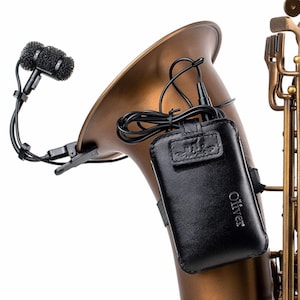 May include: A close-up of a brass-colored saxophone with a black microphone attached to the bell. A black leather case with the name "Oliver" is attached to the saxophone. The microphone has a black foam cover.