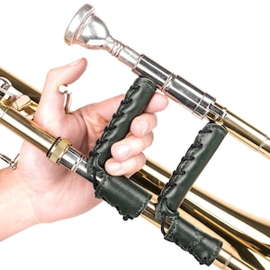 May include: A brass trombone with a silver mouthpiece and dark green leather grip covers. The covers are stitched with black thread. The instrument is held against a white background.