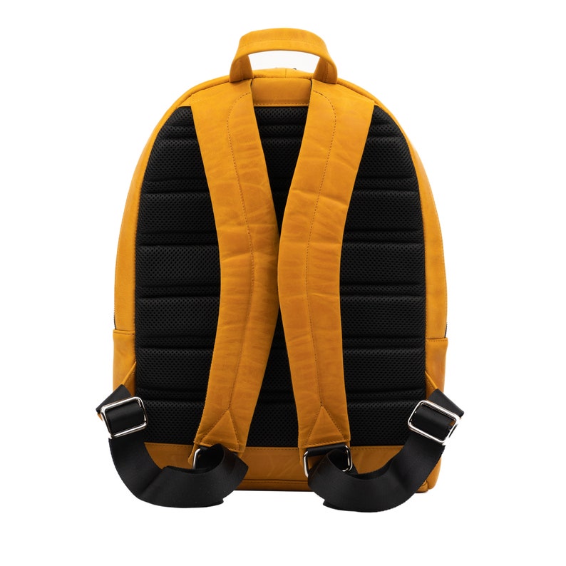 Puede incluir: Una mochila de cuero amarillo mostaza con correas ajustables negras y un panel trasero de malla negra.