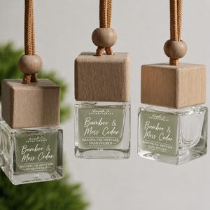 Puede incluir: Tres difusores de aceite de vidrio cuadrado para colgar con tapas de madera clara y cuentas de madera a juego en cordones beige. Cada frasco tiene una etiqueta verde salvia con el texto Kinsale Co Aromatherapy, Bamboo & Moss Cedar, 5 ml.
