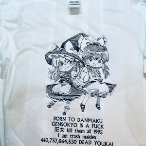 Pu&ograve; includere: Maglietta bianca con un'illustrazione in bianco e nero di due personaggi anime. Il testo sulla maglietta recita "BORN TO DANMAKU GENSOKYO IS A FUCK 巫女 kill them all 1995 I am trash maiden 410,757,864,530 DEAD YOUKAI".