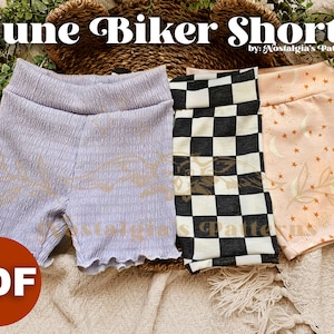 May include: Three pairs of "June Biker Shorts" sewing patterns in different fabric designs: a light purple pair with a subtle pattern, a black and white checkered pair, and a peach pair with a star and crescent moon pattern. The text "June Biker Shorts" and "by: Nostalgia's Patterns" is visible at the top of the image. The word "PDF" is in a red circle at the bottom left of the image.