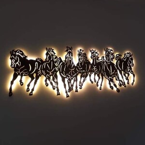 May include: A wall decoration featuring a silhouette of eight black horses running in a line, illuminated from behind with warm white light.