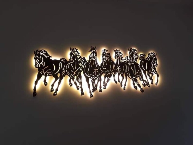 May include: A wall decoration featuring a silhouette of eight black horses running in a line, illuminated from behind with warm white light.