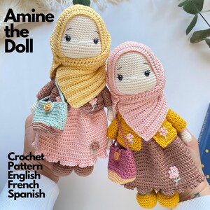 May include: Two handmade crochet dolls featuring Amine the Doll. One wears a yellow hijab, brown jacket, and pink skirt with a light blue bag. The other wears a pink hijab, yellow jacket, and brown skirt with a pink bag. Text reads Amine the Doll.