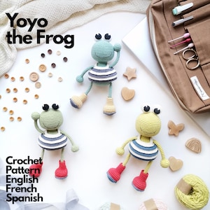Peut inclure: Trois poupées grenouilles crochetées avec des têtes rondes, des yeux noirs et blancs et des chemises rayées. Les grenouilles ont des membres et portent des bottes rouges, bleues ou beiges. Le texte Yoyo the Frog et Crochet Pattern English French Spanish est visible.