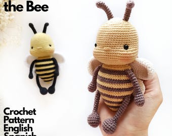 May include: Two crocheted bee dolls, one held in a hand and one resting nearby. The bees feature round heads, antennae, and striped bodies in shades of yellow, black, and brown with white wings. Text reads Luna the Bee Crochet Pattern English Spanish French.