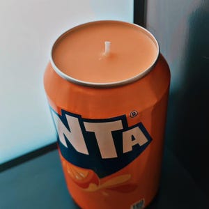 May include: Orange scented candle in a vintage-style aluminum can with the word "FANTA" printed on the side.