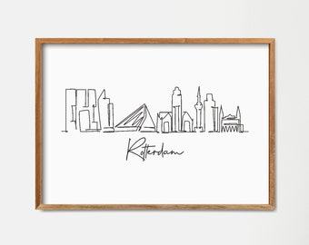 May include: A black and white line drawing of the Rotterdam skyline. The drawing is framed in a light wood frame and is hanging on a white wall.