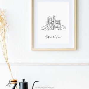 May include: A black and white line drawing of the Pena Palace in Sintra, Portugal. The drawing is framed in a light wood frame and hanging on a white wall. The text "Estrada da Pena" is written below the drawing.