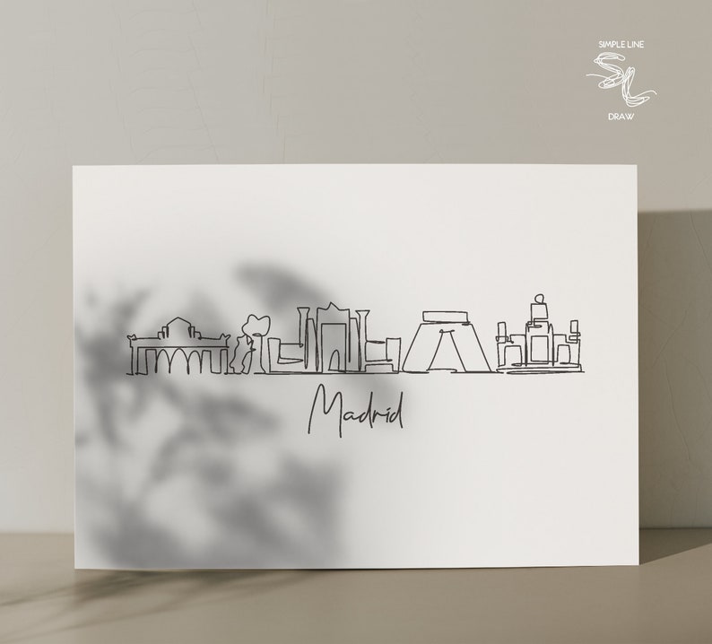 May include: A minimalist black line drawing of the Madrid skyline on a white background. The word "Madrid" is written in cursive below the skyline. The upper right corner features the text "SIMPLE LINE DRAW" and a stylized logo.