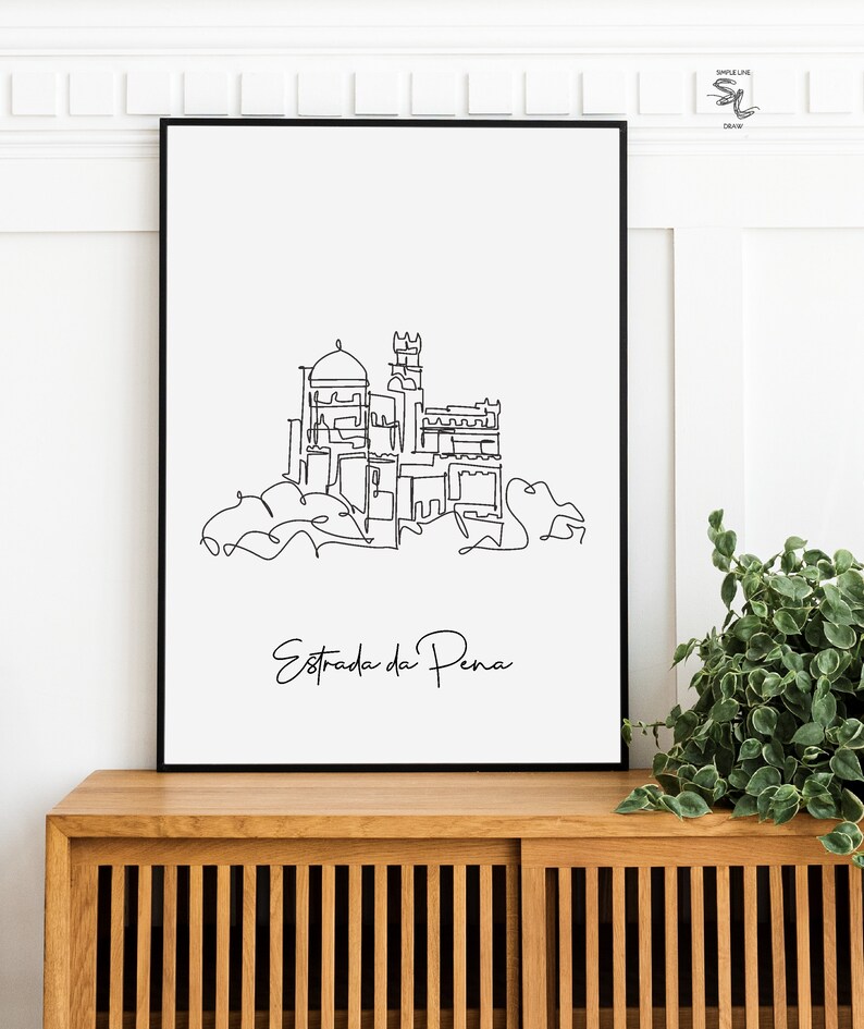 May include: Black and white line art print of the Pena Palace in Sintra, Portugal. The print is framed and hanging on a wall above a wooden cabinet. The text "Estrada da Pena" is written below the image.