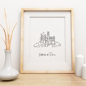 May include: A black and white line drawing of the Pena Palace in Sintra, Portugal. The drawing is framed in a light wood frame and is hanging on a white wall. The text "Estrada da Pena" is written below the drawing.