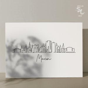 Puede incluir: Un dibujo en blanco y negro de la l&iacute;nea del horizonte de Macon, Georgia. El dibujo incluye los edificios m&aacute;s reconocibles de la ciudad, incluido el Macon City Auditorium y el Macon Coliseum. El dibujo est&aacute; titulado "Macon" en cursiva.