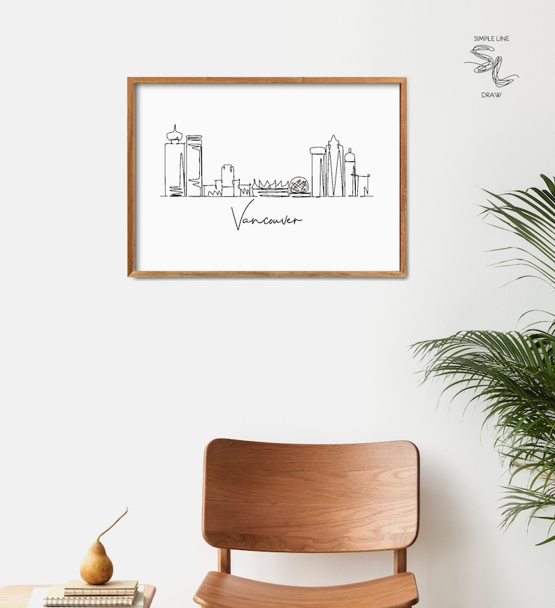 Puede incluir: Un dibujo en blanco y negro de la l&iacute;nea del horizonte de Vancouver enmarcado. El dibujo est&aacute; en un estilo de l&iacute;nea simple e incluye el texto "Vancouver" debajo del horizonte.