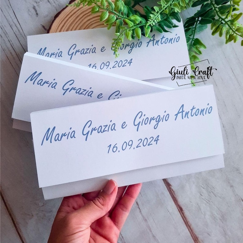 Op de afbeelding: Twee witte enveloppen met blauwe kalligrafie waarop "Maria Grazia e Giorgio Antonio" en de datum "16.09.2024" staan.