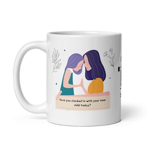 May include: White ceramic mug with a colorful illustration of two women embracing. The text on the mug reads "Have you checked-in with your inner child today?"