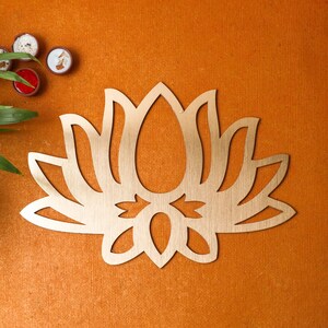 May include: A gold-colored metal lotus flower wall decor with a detailed design. The lotus flower is a symbol of purity, enlightenment, and rebirth.