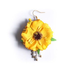 May include: Yellow flower earring with a pearl and gold bead drop. The flower is made of fabric and has a green leaf accent.